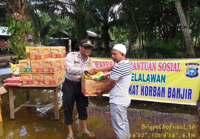 Kapolseksubsektor Pelalawan Ipda Zumaheri.SH.MH saat menyerahkan bantuan banjir pada masyarakat di Kecamatan Pelalawan, Minggu (5/1/2020). 